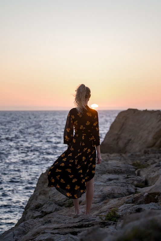 Woman standing near a cliff in front of the mediterranean sea